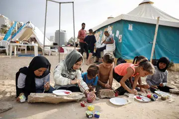 Kanak-kanak mengisi masa terluang  dengan kegiatan melukis di halaman dekat khemah-khemah perlindungan keluarga masing-masing di pantai dekat Beirut, Lebanon.
