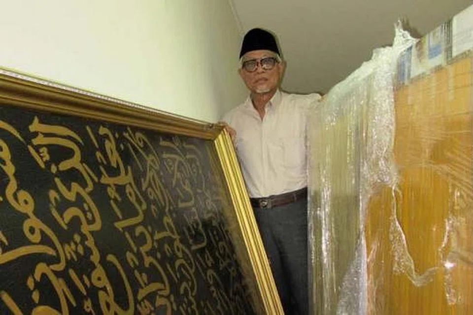 MASIH DALAM KEADAAN BAIK: Haji Hasan bersama dua keping khat ayat-ayat Al-Quran yang pernah menghiasi dinding Masjid Maarof dan kini disimpan di Rumah Peripensis di Onan Road. - Foto-foto ihsan Haji Hasan Wahyuni