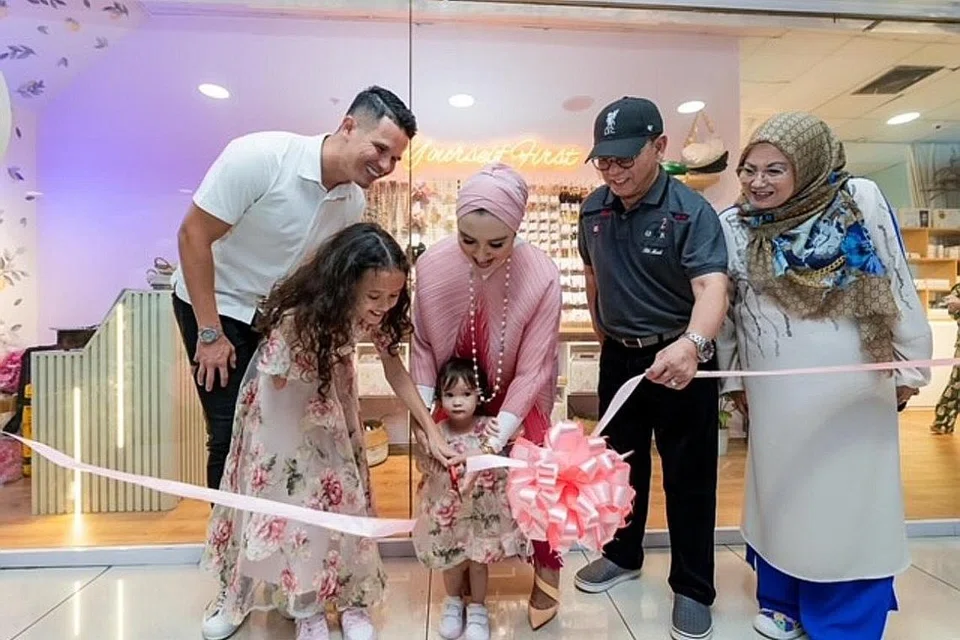 DIRASMI: Moza (depan, kiri) mengiring ibunya, Norfasarie, memotong reben bagi perasmian kedainya, Myla Moza, disaksikan bapanya, Baihakki Khaizan (kiri) dan neneknya,Cik Zaliha Rawi dan datuk, Encik Yan Amin. - Foto MUHAMMAD HASIF AZMI