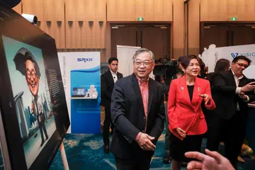 Timbalan Perdana Menteri, Encik Gan Kim Yong, melihat karikatur yang dihasilkan kecerdasan buatan (AI) semasa meninjau reruai Microsoft di hotel Pan Pacific Singapore pada 21 Mei. Bersamanya ialah Pengarah Urusan, Microsoft Singapore, Cik Lee Hui Li (baju merah).
