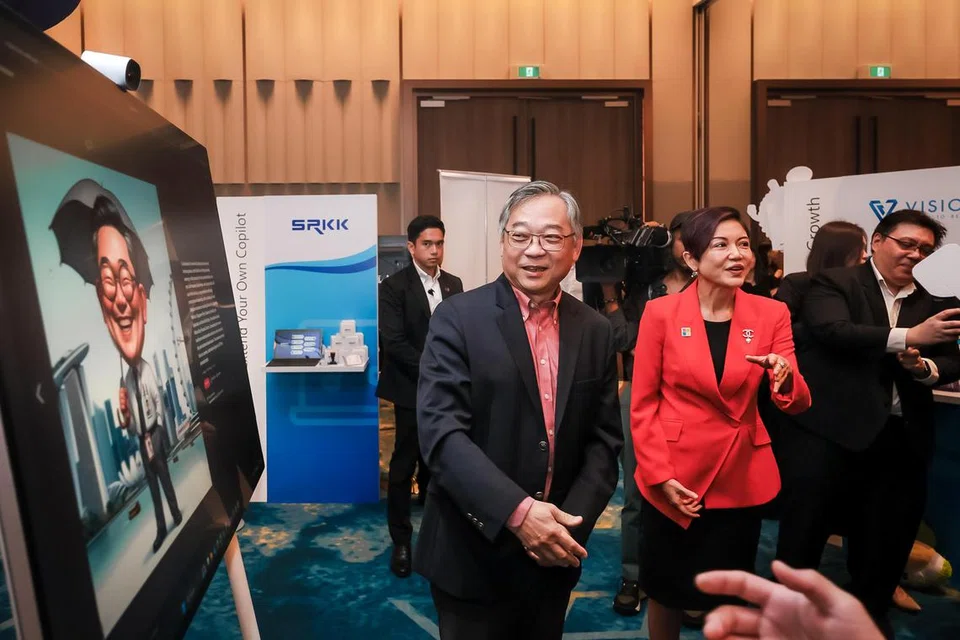 Timbalan Perdana Menteri, Encik Gan Kim Yong, melihat karikatur yang dihasilkan kecerdasan buatan (AI) semasa meninjau reruai Microsoft di hotel Pan Pacific Singapore pada 21 Mei. Bersamanya ialah Pengarah Urusan, Microsoft Singapore, Cik Lee Hui Li (baju merah).
