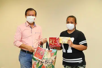 KECERIAAN SEMPENA PERAYAAN: Penasihat Akar Umbi Hougang, Encik Lee Hong Chuang (kiri), mengagihkan pek hadiah kepada seorang benefisiari, yang hanya ingin dikenali sebagai, Cik Suzana, semalam. - Foto PEJABAT KAWASAN UNDI HOUGANG