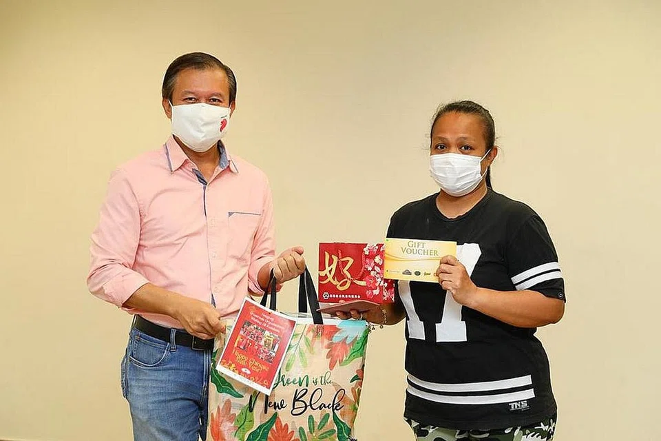 KECERIAAN SEMPENA PERAYAAN: Penasihat Akar Umbi Hougang, Encik Lee Hong Chuang (kiri), mengagihkan pek hadiah kepada seorang benefisiari, yang hanya ingin dikenali sebagai, Cik Suzana, semalam. - Foto PEJABAT KAWASAN UNDI HOUGANG