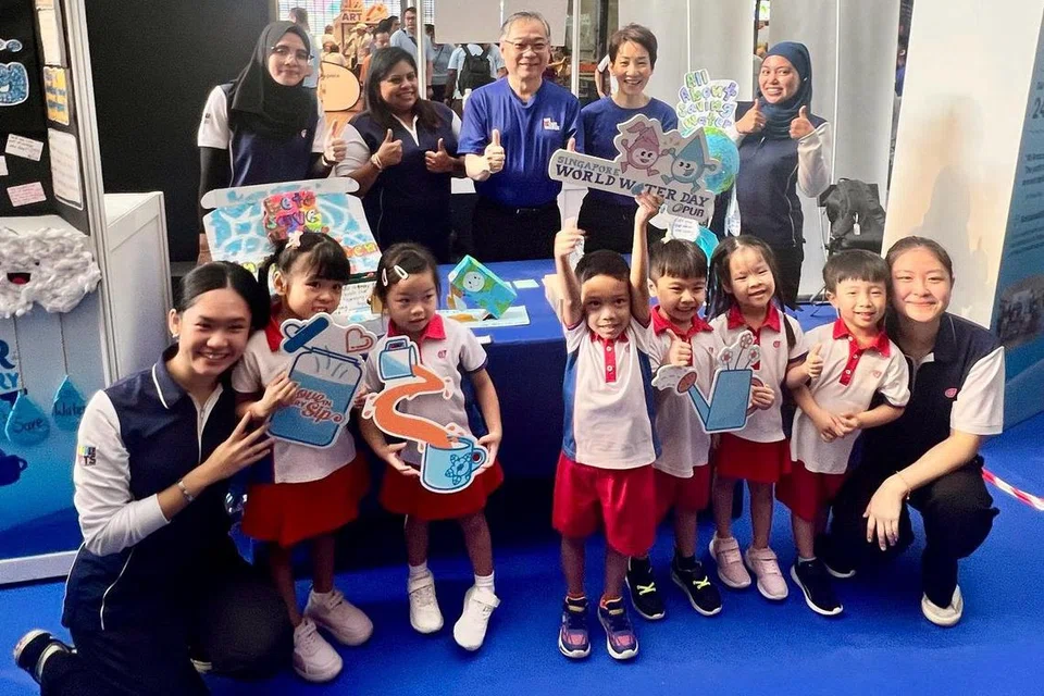 Timbalan Perdana Menteri (DPM) merangkap Menteri Perdagangan dan Perusahaan, Encik Gan Kim Yong (berdiri tiga dari kanan) dan Menteri Kemampanan dan Sekitaran, Cik Grace Fu (berdiri dua dari kanan) bergambar bersama guru dan kanak-kanak dari PCF Sparkletots@Jurong Central beserta karya seni mereka. 