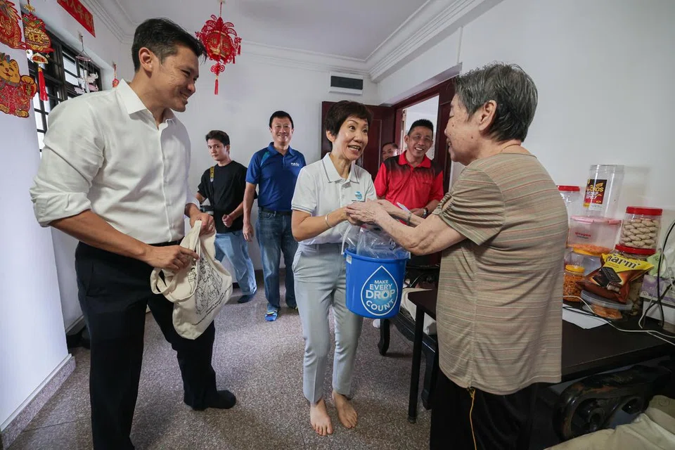 Menteri Kemampanan dan Sekitaran, Cik Grace Fu (tiga dari kanan), mengedarkan beg air kepada penduduk Taman Jurong di rumah mereka apabila bekalan air diberhentikan buat sementara dari 9 hingga 11 pagi pada 26 Februari sebagai sebahagian simulasi gangguan bekalan kepada makanan dan air.
