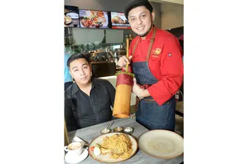 RASA BERBEZA: Cef Syed Shah (kanan) bersama seorang pengunjung restoran, menunjukkan nasi beriani rekaannya yang dimasak di dalam buluh dan merupakan gabungan bahan dari tiga negara - India, Australia dan Pakistan. Ia kini terdapat di restoran 99Bistro di Institut Pembelajaran Sepanjang Hayat berdekatan stesen MRT Paya Lebar. - Foto JOHARI RAHMAT