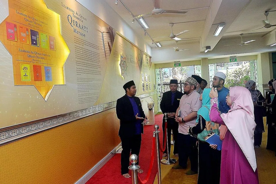 BERI PENERANGAN: Ustaz Azzahir Ariffin (kiri) menerangkan galeri mengenai program Al-Quran yang terdapat di Masjid Mujahidin kepada ahli lembaga masjid dari Terengganu itu. 