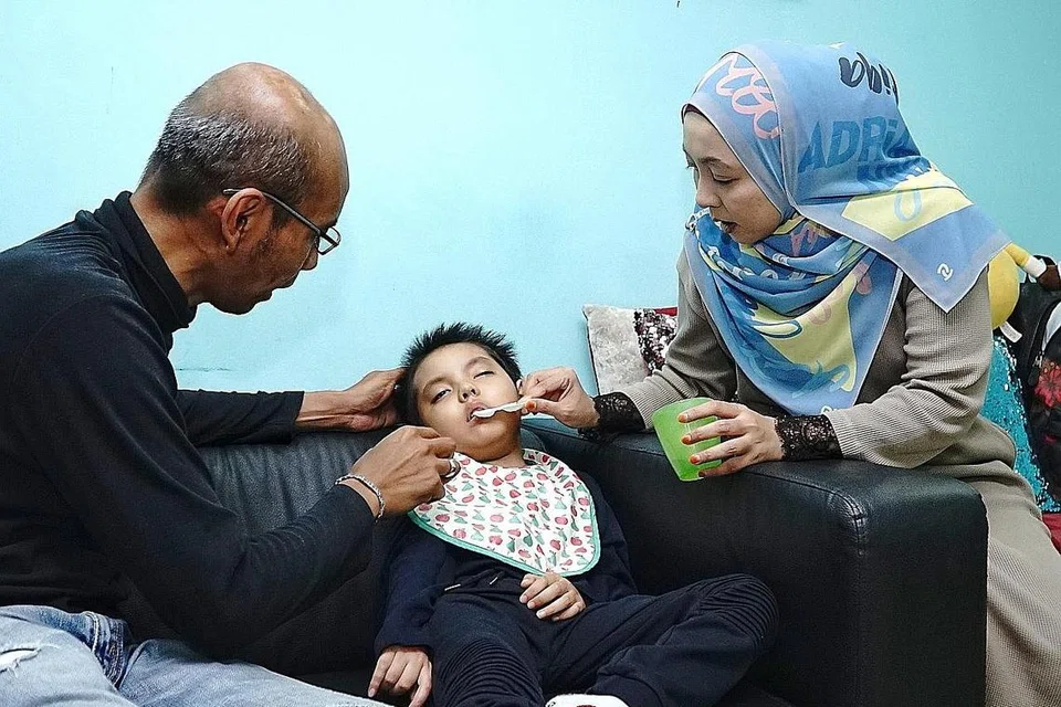 TIDAK BERPUTUS ASA: Encik Mohamad Nazri dan isterinya Cik Nur Haslindah kelihatan memberikan air kepada anak mereka Mohamad Aryan Haqim, enam tahun, yang tidak berupaya bergerak, berjalan dan bertutur ekoran tumbuhan di otaknya. - Foto BH oleh KHALID BABA