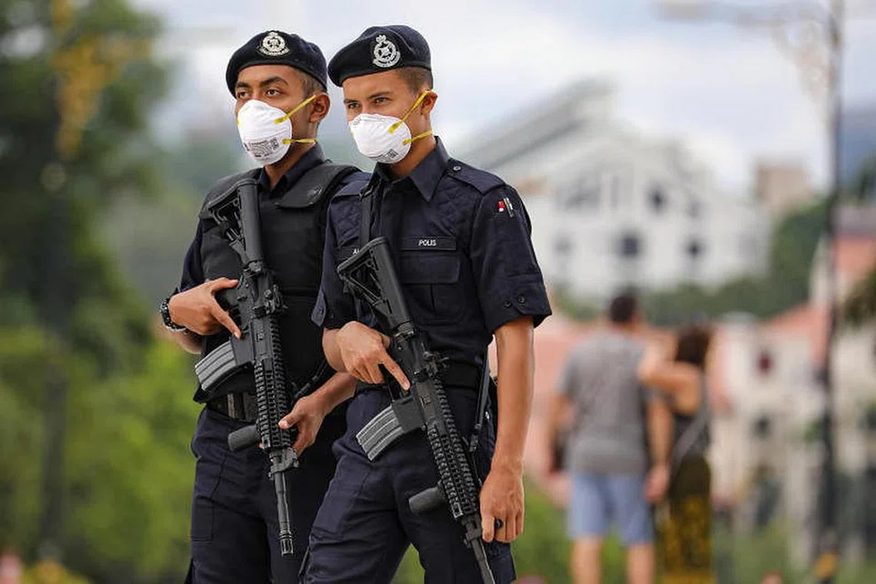 Pegawai polis Malaysia menggunakan pelitup muka semasa menjalankan tugas berikutan wabak koronavirus COVID-19. FOTO: REUTERS