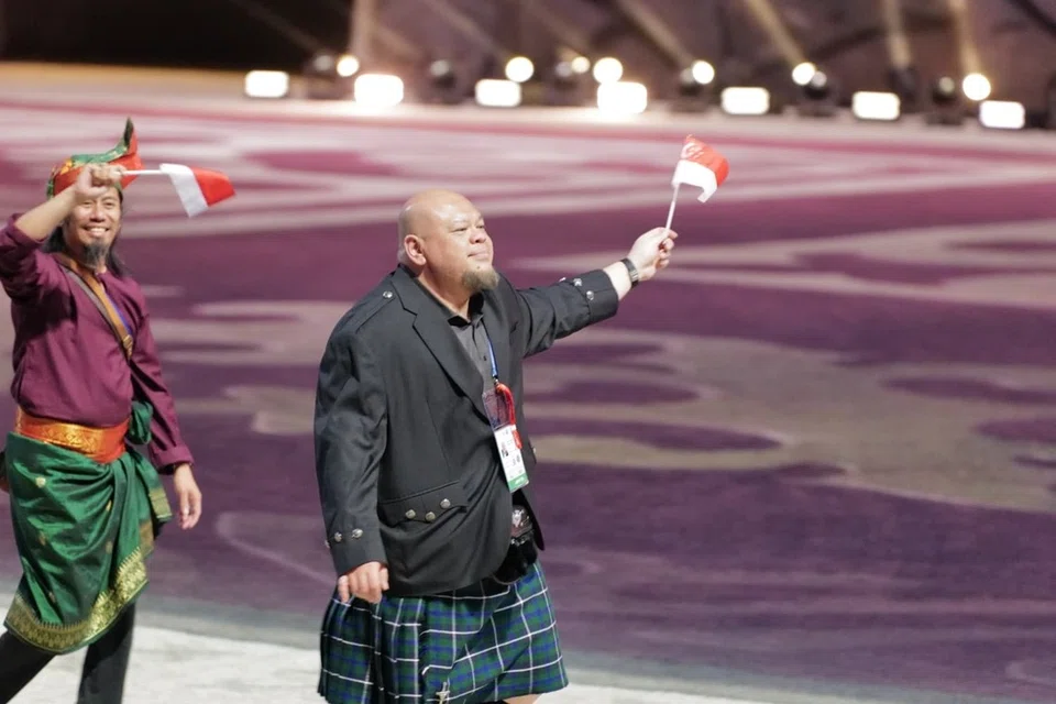 Encik Ahmad Taufiq Muhammad melambai bendera Singapura di Acara pembukaan Sukan Nomadik Dunia 2026