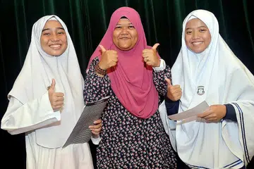 CEMERLANG DALAM PELAJARAN DAN JUGA HIDUP: Antara pelajar terbaik Madrasah Al-Maarif, Hazirah Nurfitrah Mohamed Hanifar (kiri) dan juga Nabilah Farhah Ali (kanan) yang bergambar dengan guru mereka, Cik Juydah Noor Mohd. Nabilah Farhah juga merupakan pelajar madrasah terbaik secara keseluruhan. - Foto KHALID BABA