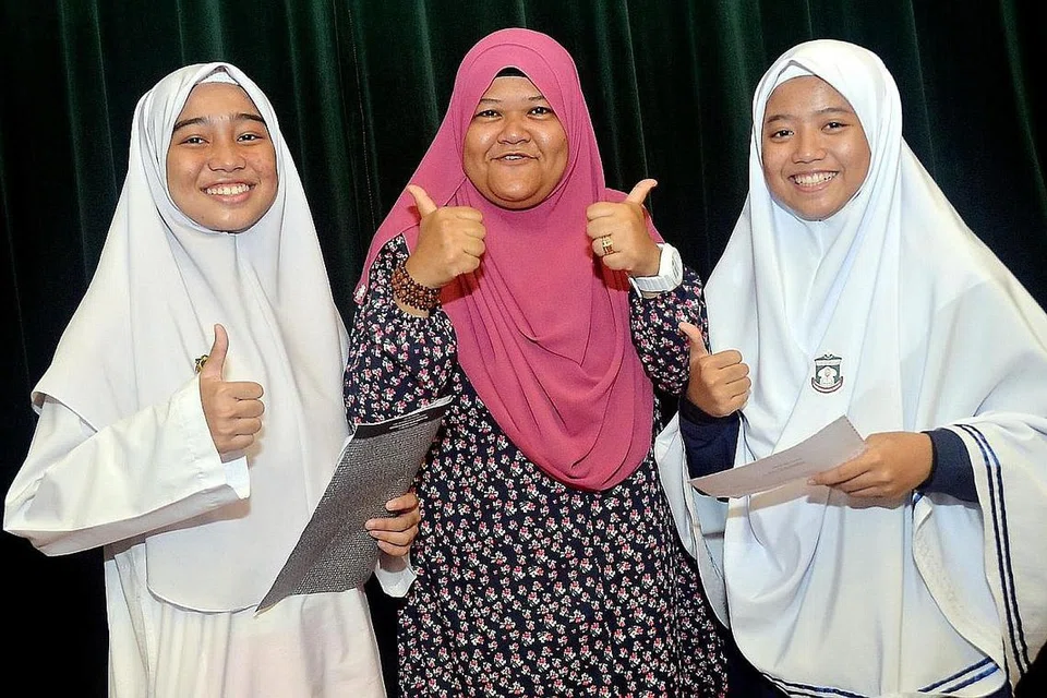CEMERLANG DALAM PELAJARAN DAN JUGA HIDUP: Antara pelajar terbaik Madrasah Al-Maarif, Hazirah Nurfitrah Mohamed Hanifar (kiri) dan juga Nabilah Farhah Ali (kanan) yang bergambar dengan guru mereka, Cik Juydah Noor Mohd. Nabilah Farhah juga merupakan pelajar madrasah terbaik secara keseluruhan. - Foto KHALID BABA