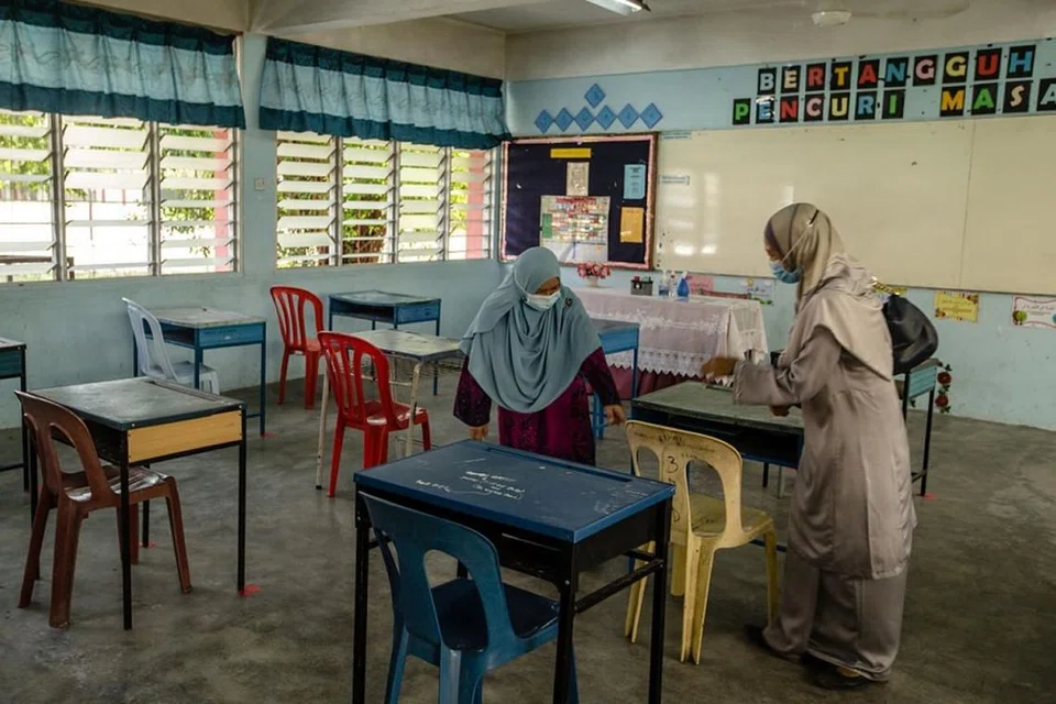 PASTIKAN JARAK SELAMAT DIPATUHI: Para guru menyusun meja dalam bilik darjah mengikut aturan jarak selamat di Sekolah Menengah Kebangsaan Seksyen 19 di Shah Alam, semalam. - Foto THE MALAY MAIL