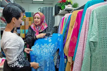 PELBAGAIKAN NIAGA: Cik Maimunah (kanan) lebih menumpukan perhatian menerima tempahan menjahit di samping menjual pakaian yang sudah siap di butiknya. - Foto BM oleh ZALEHA ABDUL KADER