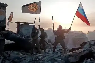 BERAKHIRNYA PERTEMPURAN?: Askar upahan Kumpulan Wagner mengibarkan bendera kebangsaan Russia dan bendera Kumpulan Wagner di atas bumbung bangunan yang rosak di Bakhmut, Ukraine. - Foto AFP
