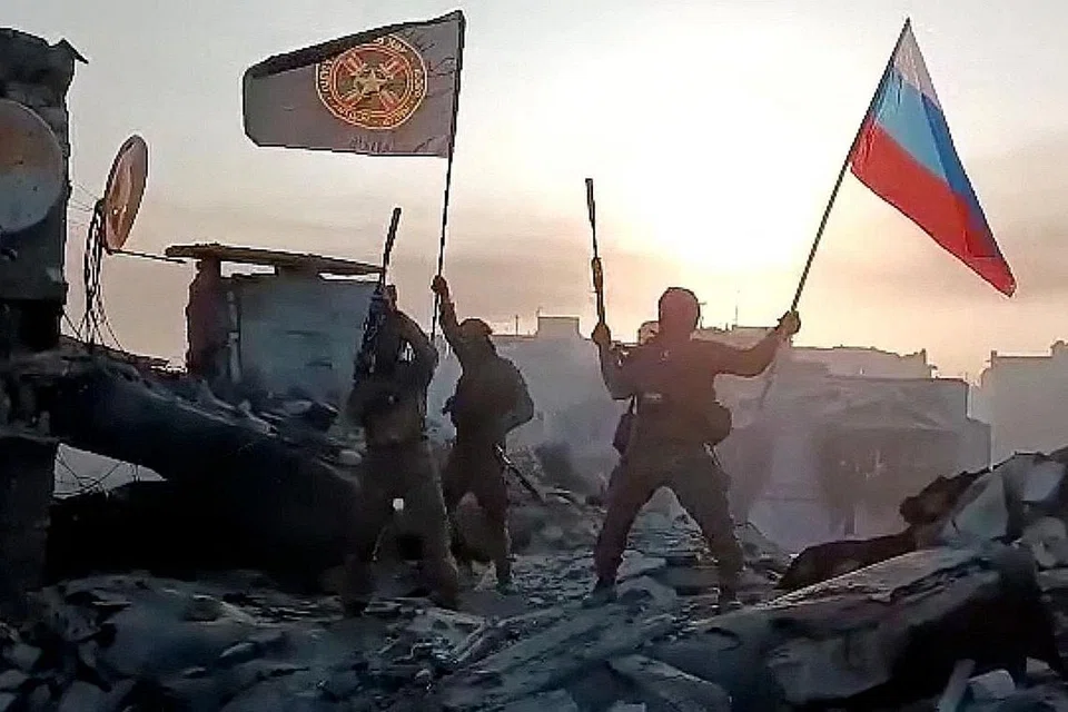 BERAKHIRNYA PERTEMPURAN?: Askar upahan Kumpulan Wagner mengibarkan bendera kebangsaan Russia dan bendera Kumpulan Wagner di atas bumbung bangunan yang rosak di Bakhmut, Ukraine. - Foto AFP