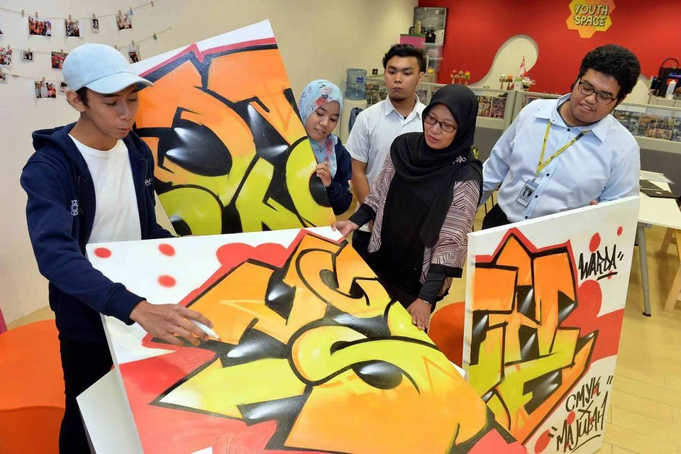 RUANG BELIA: Penolong Pengarah Yayasan Mendaki, Cik Azlinah Arif (dua dari kanan), dan seorang pelajar Institut Pendidikan Teknikal (ITE), Encik Luqman Annuar (kanan), melihat lukisan grafiti peserta di ruang belia Youth Space - satu kerjasama antara Mendaki dengan ITE yang membantu mempersiap masyarakat Melayu/Islam bagi merebut peluang dalam ekonomi hari muka di ITE Kolej Central di Ang Mo Kio. - Foto fail