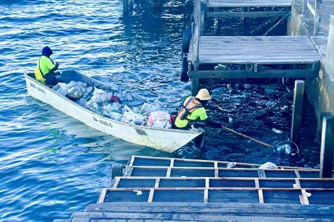 Pekerja pembersihan Majlis Daerah Semporna mengutip botol-botol plastik yang terapung di Jeti Semporna.