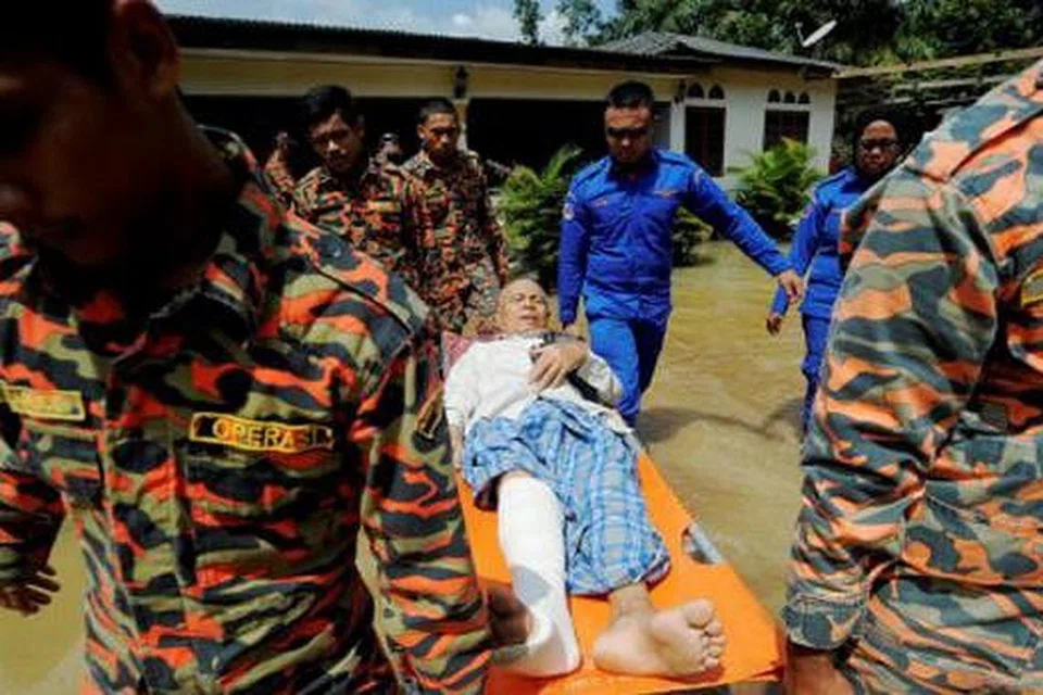 BANTUAN KECEMASAN: Anggota Bomba dan Jabatan Pertahanan Awam Malaysia mengangkat warga emas, Encik Misnan Rahimi, 78 tahun, untuk dipindahkan ke pusat perpindahan berikutan banjir yang berlaku di Kampung Parit Mahang, Selangor. - Foto NST