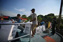 Pegawai pilihan raya mengangkut kotak undi ke Kepulauan Seribu Indonesia dengan bot pada 10 Februari. 