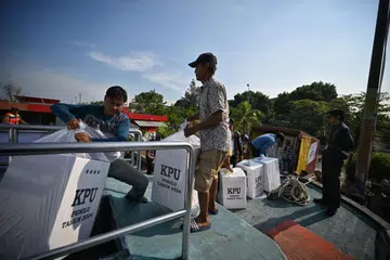 Pegawai pilihan raya mengangkut kotak undi ke Kepulauan Seribu Indonesia dengan bot pada 10 Februari. 