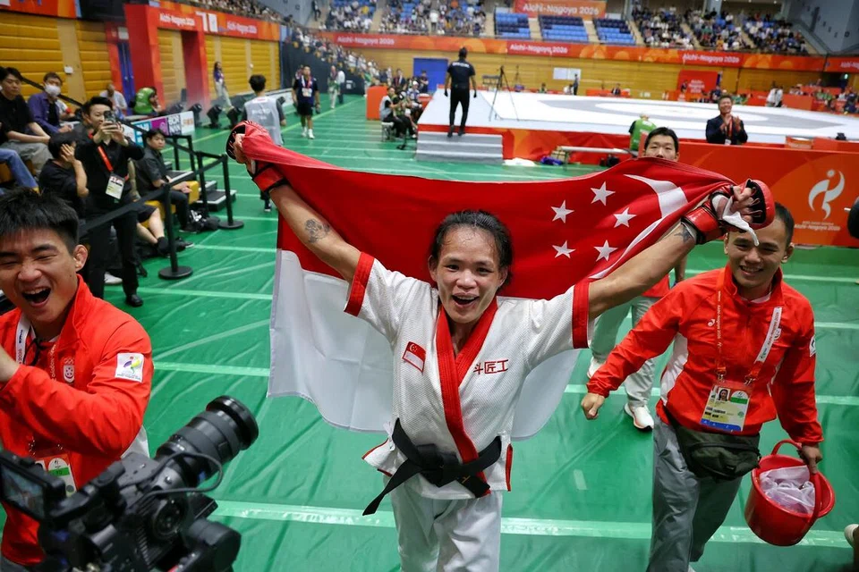 Tiffany Teo mengibarkan bendera Singapura selepas menewaskan Khilola Sobirova dari Uzbekistan dalam final MMA tradisional (60kg) wanita Sukan Asia 2026.