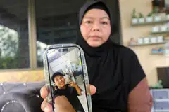 KEHILANGAN ANAK: Ibu arwah kemalangan maut, Muhammad Zaharif Affendi Muhd Zamrie, 17 tahun, Mimi Julia ismail, 50 tahun kelihatan sedih sambil menunjukkan gambar arwah anaknya di kediaman keluarganya di Taman Chepor Sentosa Chemor pada 16 Disember.