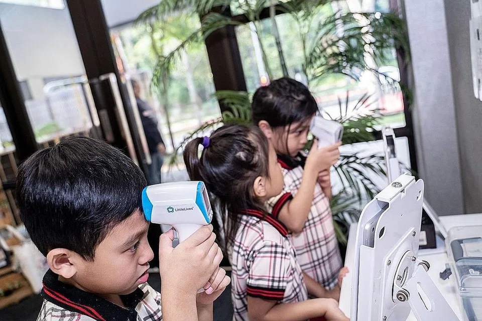 TINGKATKAN KECEKAPAN: Kanak-kanak di PPIS Bukit Batok sedang mengambil suhu badan sendiri menggunakan alat yang disediakan, sekali gus memupuk sikap berdikari dan berani menggunakan teknologi. - Foto BM oleh NUR DIYANA TAHA