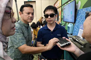 Penyelia Jabatan Pengeluaran Braille, SAVH, Encik Jason Setok (kanan), berkongsi mengenai paparan Braille kepada Menteri Negara Kanan (Pertahanan merangkap Kemampanan dan Sekitaran), Encik Zaqy Mohamad (dua dari kiri), di sidang media Raikan Ilmu 2025 di Safra Choa Chu Kang pada 27 Jun. Turut berada dalam gambar ialah Ketua Pegawai Eksekutif (CEO) Mendaki, Cik Zuraidah Abdullah (paling kiri). 