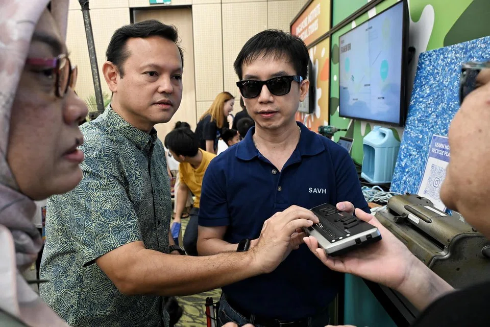 Penyelia Jabatan Pengeluaran Braille, SAVH, Encik Jason Setok (kanan), berkongsi mengenai paparan Braille kepada Menteri Negara Kanan (Pertahanan merangkap Kemampanan dan Sekitaran), Encik Zaqy Mohamad (dua dari kiri), di sidang media Raikan Ilmu 2025 di Safra Choa Chu Kang pada 27 Jun. Turut berada dalam gambar ialah Ketua Pegawai Eksekutif (CEO) Mendaki, Cik Zuraidah Abdullah (paling kiri). 