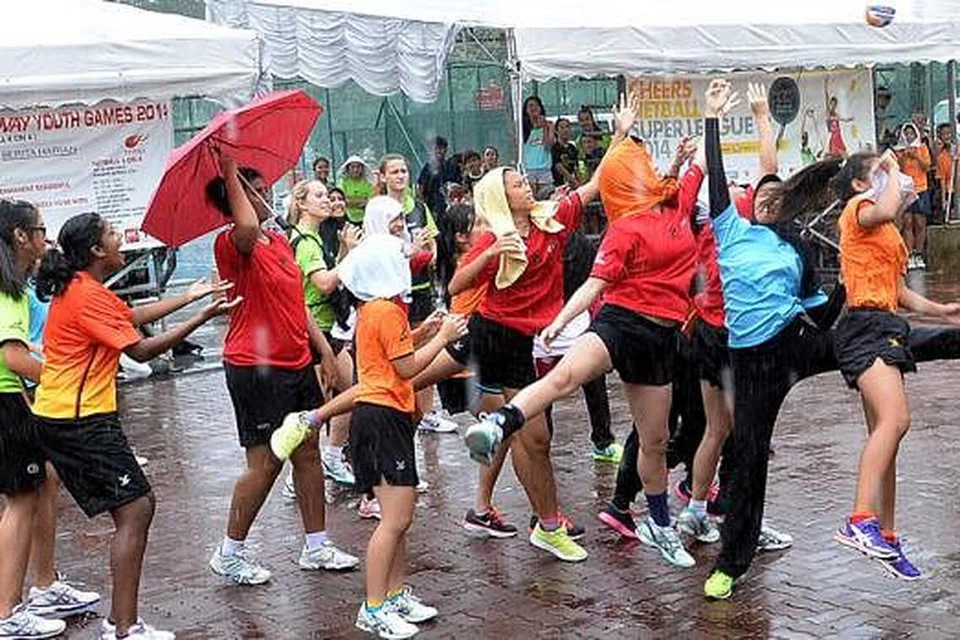 BERSEMANGAT: Meskipun hujan, para peserta pertandingan bola jaring Sukan Belia Berita Harian/Pilot Pen/Ashaway tetap bersemangat menunjukkan taring di tengah gelanggang. - Foto TAUFIK A. KADER
