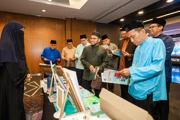 Mufti Dr Nazirudin Mohd Nasir (tengah) dan Presiden Majlis Ugama Islam Singapura (MUIS), Encik Mohamed Saat Abdul Rahman (kanan) bersama kakitangan MUIS meninjau kegiatan sampingan sempena Seminar QuranSG di Pusat Konvensyen Suntec pada 24 Oktober.