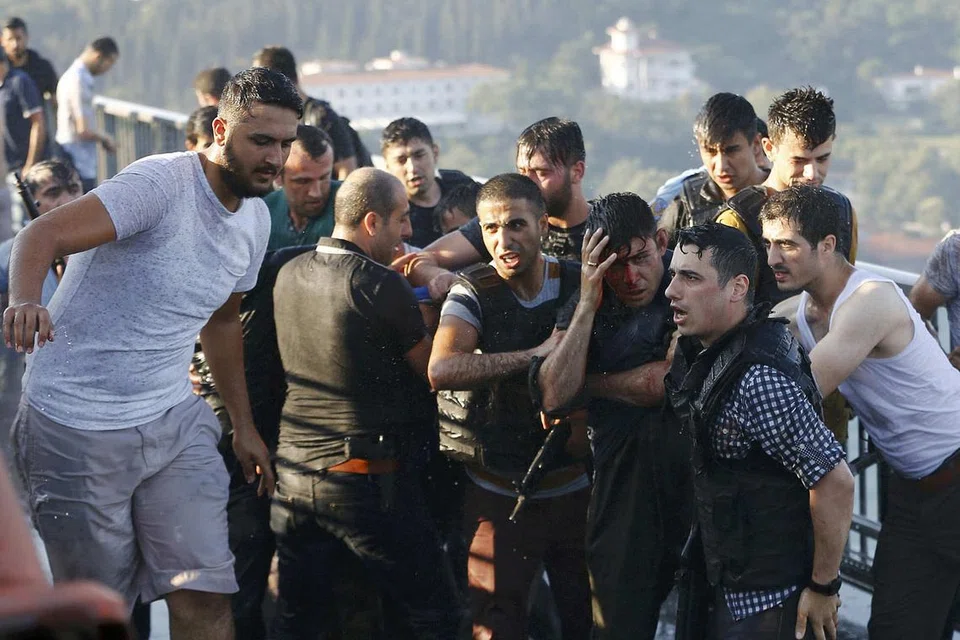 MENYERAH DIRI: Polis melindungi seorang askar yang terlibat dalam kudeta daripada diserang orang ramai selepas dia dan rakan-rakan sekongkolnya menyerah diri di Jambatan Phosphorus di Istanbul semalam. - Foto REUTERS