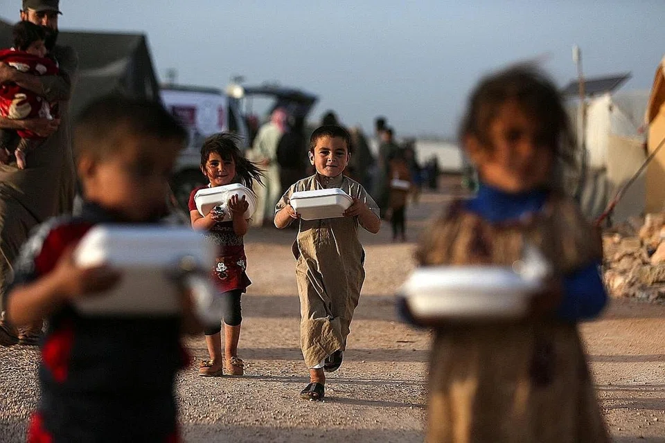 GEMBIRA DAPAT JUADAH BERBUKA: Kanak-kanak Syria yang tinggal di khemah pelarian bergembira mendapat kotak makanan yang diedarkan pertubuhan amal sebelum berbuka puasa, di sebuah khemah berdekatan sempadan Syria-Turkey. - Foto AFP 