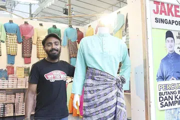 IMPORT DARI MALAYSIA: Encik Muhammad Syaheer memaparkan dua koleksi pakaian baju kurung Awal Ashaari dan Aaron Aziz yang diimport dari Malaysia. - Foto NUR HUMAIRA SAJAT