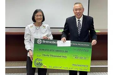 DURIAN RUNTUH: Ketua Pegawai Eksekutif Sheng Siong Lim Hock Chee menyerahkan cek bernilai $30,000 kepada Cik Sumaiya Abdullah. Cik Sumaiya membelanjakan $150 dan mengisi lima borang cabutan bertuah. - Foto SHENG SIONG