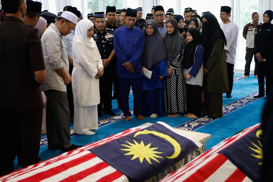 Raja Permaisuri Agong Raja Zarith Sofiah (berbaju putih) memberi penghormatan terakhir kepada jenazah Konstabel Ahmad Azza Fahmi Azhar dan Konstabel Muhamad Syafiq Ahmad Said, di Masjid Tunku Laksamana Abdul Jalil Ibu Pejabat Polis Kontinjen Johor pada 18 Mei. Turut hadir Menteri Dalam Negeri Datuk Seri Saifuddin Nasution Ismail (tiga dari kiri). Jenazah dua anggota polis yang maut dalam serangan di Balai Polis Ulu Tiram awal pagi 17 Mei itu kemudiannya dibawa ke kampung halaman masing-masing di Bidor, Perak dan Kuantan, Pahang.