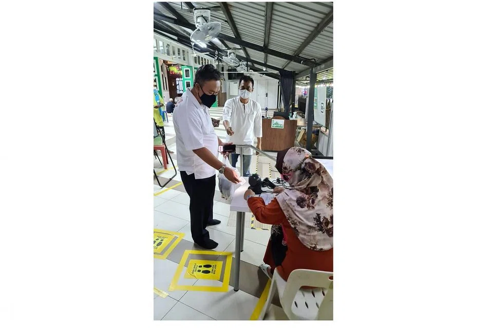 TELITI IKUT PERATURAN: Encik Abu Bakar Abdullah (tengah), relawan selama tiga tahun di Masjid Kampong Delta, memastikan langkah pengurusan selamat diikuti. Dalam gambar, Encik Abu Bakar dilihat mahu menyemak tempahan slot jemaah. - Foto ihsan ABU BAKAR ABDULLAH