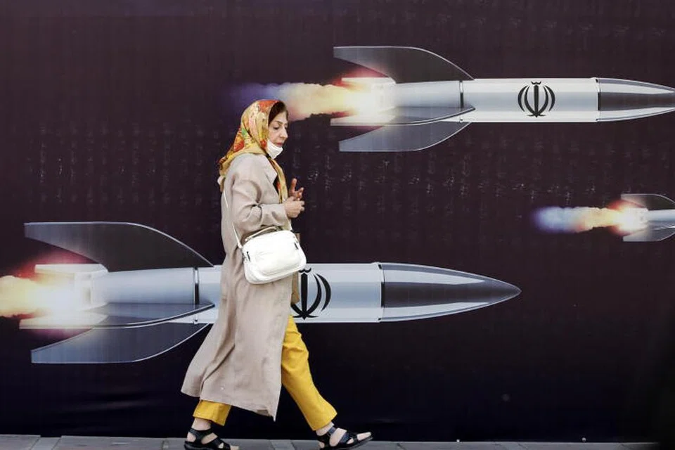 Seorang wanita Iran berjalan di hadapan sepanduk besar anti-Israel yang membawa gambar peluru berpandu, di Teheran, Iran, pada 19 April.