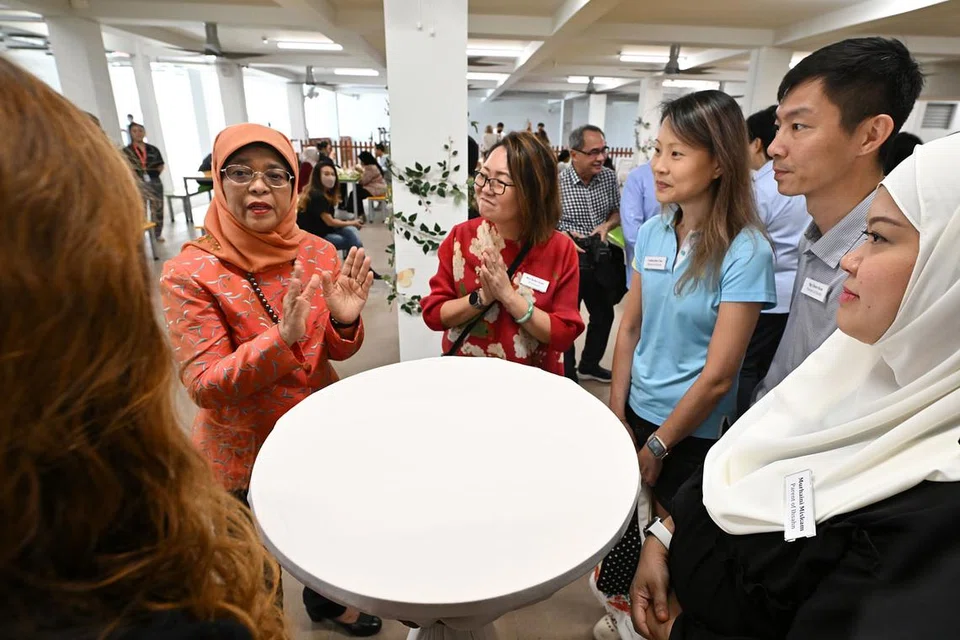EKOSISTEM MENYELURUH: Presiden Halimah (dua dari kiri) bercakap dengan ibu bapa yang menghantar anak yang mempunyai ASD ke Sekolah AWWA di Bedok. Beliau menekankan pentingnya ekosistem menyeluruh untuk membolehkan individu berkeperluan khas berkembang maju. Bersamanya Pengetua Sekolah AWWA @ Bedok, Cik Ruby Seah (tiga dari kiri) - Foto BH oleh LIM YAOHUI