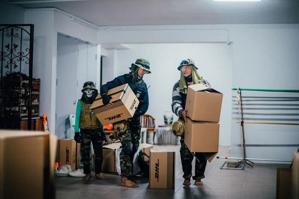 SEDIAKAN GELANGGANG: Anak bongsu Mohamad Luqman Mohamad Munir, 12 tahun, anak keempat Ahmad Abdullah Mohamad Munir, 18 tahun dan Encik Mohamad Munir Rohani kelihatan sedang menyusun kotak-kotak sebagai papan sasaran kegiatan tembak-menembak mereka di lobi lif di luar rumah lima-bilik mereka di Pasir Ris.