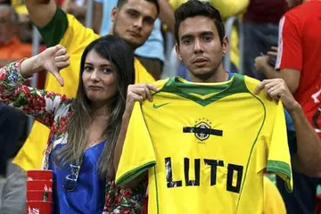 SEDIH BERTUKAR JADI MARAH: Dua penyokong Brazil memegang jersi yang ditulis kekata bermaksud 'Berkabung' sambil menunjukkan isyarat kecewa semasa perlawanan menentang Belanda di Brasilia awal pagi semalam. - Foto REUTERS