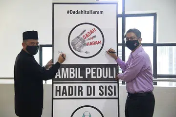 MESEJ BARU: Menteri Negara (Ehwal Dalam Negeri merangkap Pembangunan Negara), Profesor Madya Dr Muhammad Faishal Ibrahim (kanan) bersama Pengurus Besar Kelompok Masjid Bahagian Utara, Encik Yacob Ahmad, menandatangani sepanduk dengan mesej baru Dadah Itu Haram di Masjid Darul Makmur semalam. - Foto CNB 