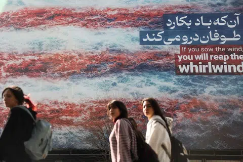Wanita Iran berjalan melintasi papan iklan anti Amerika Syarikat di Teheran, Iran, 19 Februari 2026. 