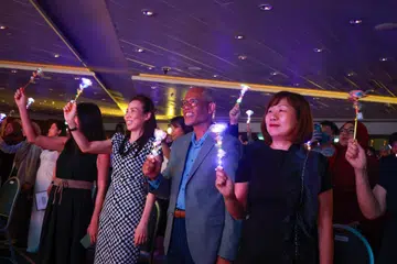 Menteri Pembangunan Sosial dan Keluarga, Encik Masagos Zulkifli, diapit Penolong Ketua Eksekutif (Profesional) Agensi Pembangunan Awal Kanak-Kanak (ECDA), Cik Caroline Seng (kiri), dan Ketua Eksekutif ECDA, Cik Ku Geok Boon (kanan), melambaikan bunga bercahaya sebagai sebahagian aktiviti  pada akhir majlis Penyampaian Biasiswa dan Anugerah Latihan ECDA 2026 yang diadakan di Pusat Konvensyen dan Pameran Suntec Singapura pada 13 Oktober.