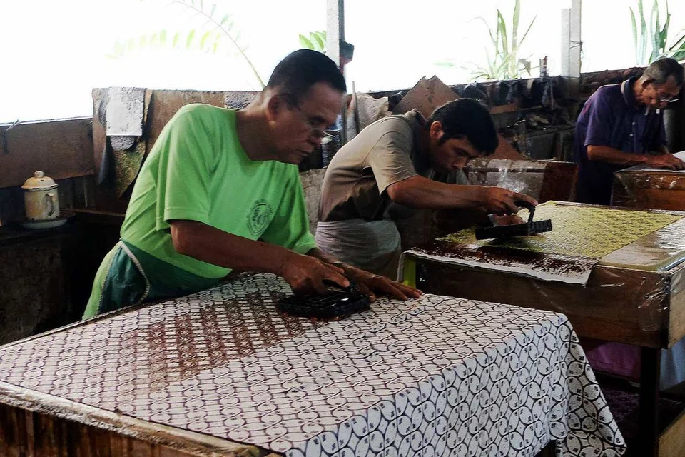 Para pekerja sedang membuat batik cap.