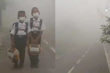 Dua anak Cik Riri Jayanti memakai pelitup muka ketika bersiap untuk ke sekolah dalam keadaan jerebu tebal di Banjarbaru, Kalimantan Selatan, pada pagi 19 Ogos 2026. Jerebu akibat kebakaran hutan dan tanah menyebabkan jarak penglihatan sangat terhad sehingga bendera merah putih di sepanjang jalan hampir tidak kelihatan. Kebakaran yang semakin menghampiri kawasan kediaman turut menyebabkan penduduk mengalami batuk dan masalah pernafasan, sementara waktu persekolahan terpaksa disesuaikan mengikut keadaan jerebu.