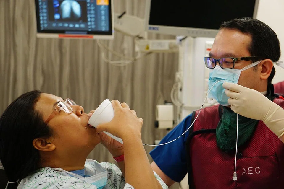 KURANGKAN BERAT BADAN TANPA PEMBEDAHAN: Dr Lim Chin Hong (kanan) membantu seorang pesakitnya, Cik Nur Shahida Suhaimi, semasa prosedur yang dikenali sebagai 'ingestible gastric balloon' pada Jun lalu. - Foto SGH