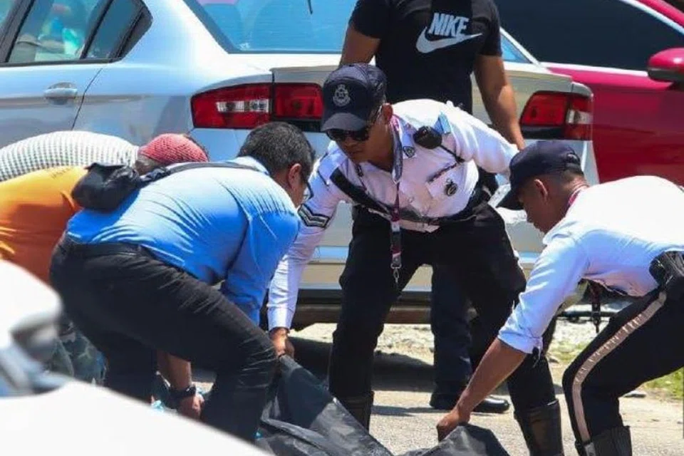 Anggota polis mengangkat mayat Allahyarham Farhan Harith Che Fauzi, 30 tahun, yang meninggal dunia selepas dirempuh sebuah lori ketika sedang berhenti di simpang lampu isyarat di Kota Bharu, Kelantan. 