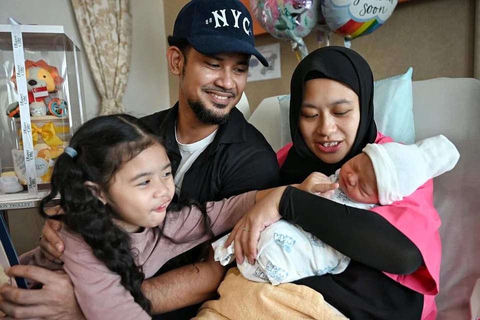 Cik Nur Atika Osman (kanan) dan suaminya, Encik Muhammad Khairul Arifin Kharudin (kiri) bersama anak sulungnya, Aleeya Khaira Muhammad Khairul Arifin, menyambut kelahiran bayi Hari Kebangsaan pada 1.04 pagi di Hospital Wanita dan Kanak-kanak KK (KKH).